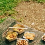 A variety of snacks and drinks placed on the grass during recess.