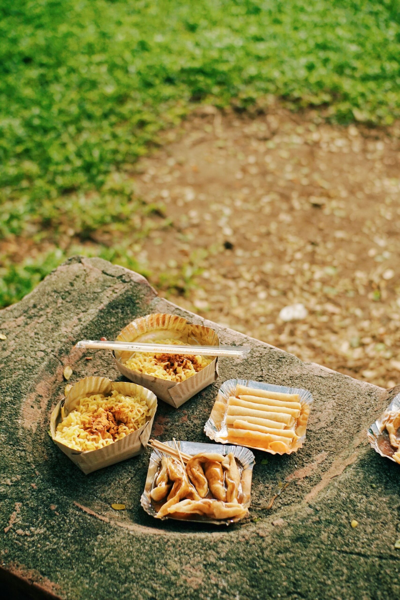 A variety of snacks and drinks placed on the grass during recess.