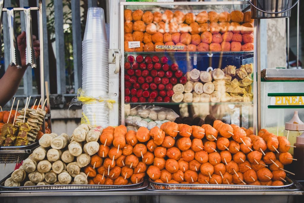 A variety of Filipino street foods, including kwek-kwek, kikiam, fish balls, and squid balls, served on skewers.